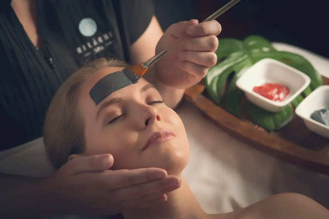 A Relâche therapist applies a facial mask to a relaxed guest